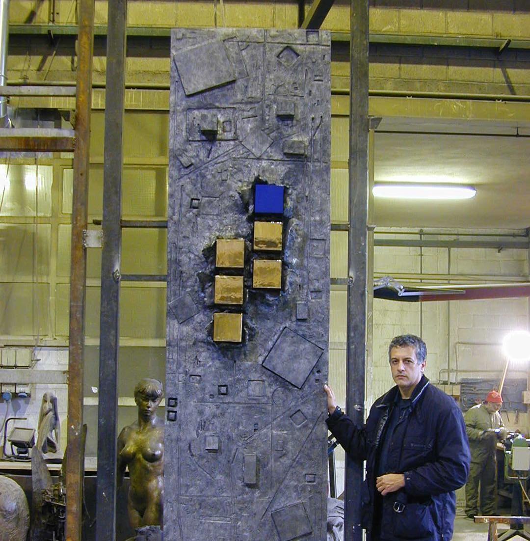 Stefano Iosca standing beside his sculpture Nextra in a foundry